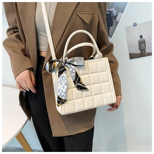 Détail du sac bandoulière beige matelassé avec foulard en soie sur la poignée