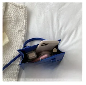 Blue leather handbag interior showing daily items like phone and lipstick for capacity display