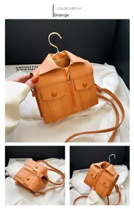 Macro detail of orange jacket-shaped crossbody bag with zipper and button accents