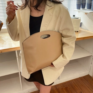 Minimalist beige smooth leather tote bag with oval cutout handle for chic urban commuting