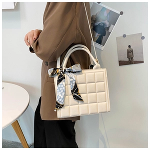 Gros plan d'un sac à main blanc matelassé avec un foulard en soie sur la poignée