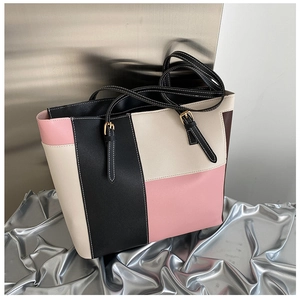 Detail of color-block tote bag featuring white contrast stitching and gold metal buckles