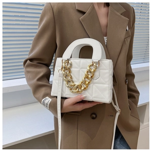 Close-up of white quilted handbag with chunky gold chain detail and top handle
