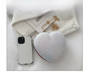 Close-up of heart-shaped glitter bag size compared with a smartphone for scale