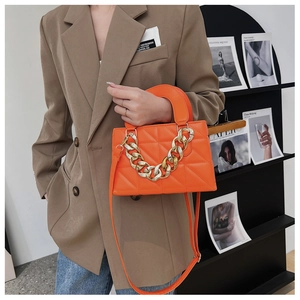 Detail of orange quilted handbag with chunky gold chain, shown styled with a khaki blazer
