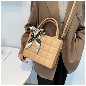 Détail du sac à main carré matelassé beige avec poignée en soie et bandoulière réglable