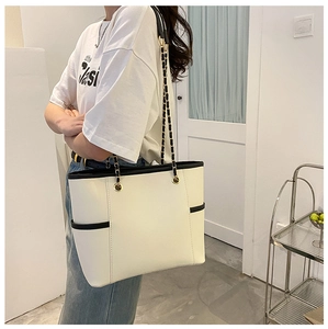Side view of cream leather tote bag with chain strap shown on model for size and scale