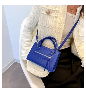 Detail view of Klein blue matte leather handbag with long fringe zipper and silver hardware