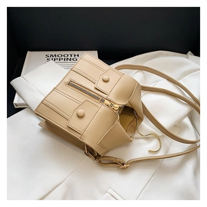 Detail of beige jacket-style shoulder bag featuring creative zipper and button pockets