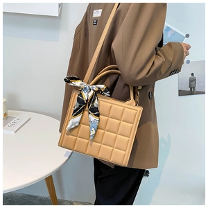 Sac à main matelassé kaki avec foulard en soie porté par un mannequin en décor épuré