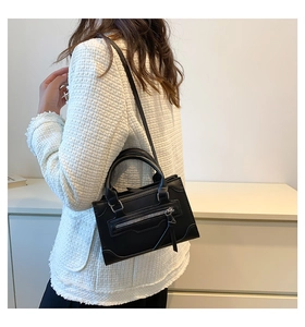 Close-up of black leather crossbody bag with silver tassel zipper and detachable shoulder strap