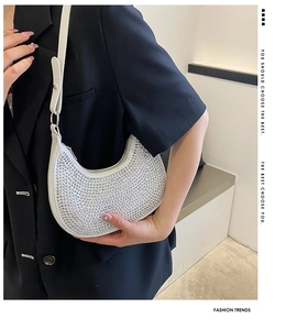 Detail view of silver rhinestone crescent bag with chain on female model shoulder