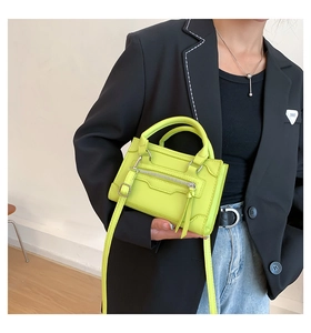 Neon green mini tote bag with silver hardware shown on model in black suit