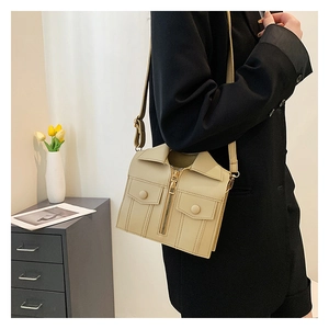 Detail view of cream jacket-shaped handbag with zipper accents worn by a model