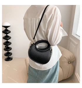 Détail d'un sac demi-lune noir plissé avec poignée ronde et finitions en métal doré