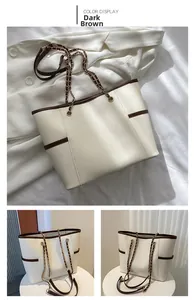 Detail of cream leather tote bag with dark brown trim and chain shoulder strap