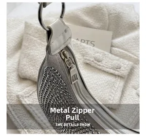 Detail showing smooth silver metal zipper puller and shiny rhinestone surface on handbag