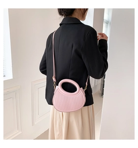 Détail d'un sac à main rose demi-circulaire avec relief rayé et poignée ronde
