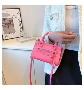 Detail of pink leather handbag showing textured surface and front zipper with tassel