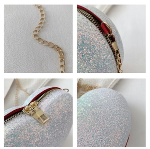 Macro details of heart-shaped sequin bag featuring gold chains and dual metal zippers