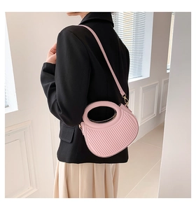 Détail du sac croissant rose montrant la texture plissée et la poignée ronde évidée
