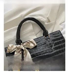 Close-up of black crocodile pattern faux leather handbag with a silk scarf handle