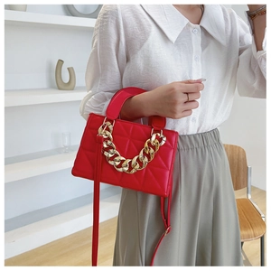 Detail of red quilted leather handbag with gold chain strap and elegant crossbody design