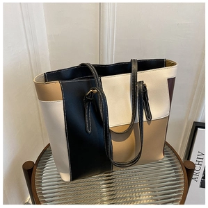 Detail of color-block tote bag showing premium faux leather texture and white contrast stitching