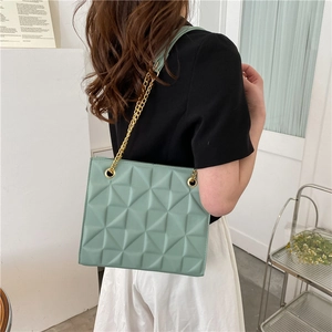 Sac fourre-tout vert menthe à losanges avec chaîne dorée porté par un mannequin