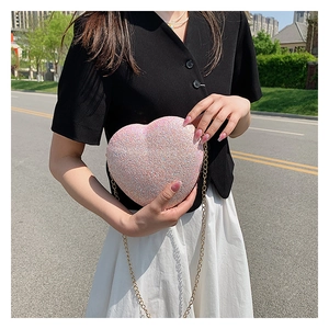 Close-up of pink iridescent sequin heart-shaped bag with delicate gold chain strap