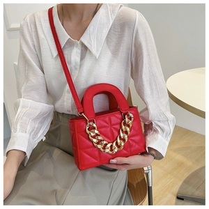 Close-up of red quilted leather bag with thick gold chain and stylish shoulder strap
