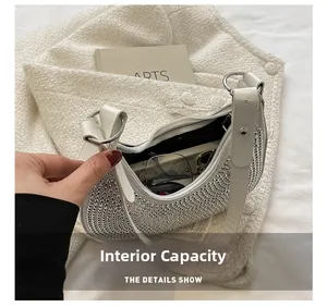 Internal capacity of the white rhinestone underarm bag showing space for phone and glasses