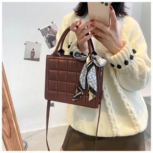 Détail du sac bandoulière matelassé marron foncé avec poignée décorative en foulard de soie