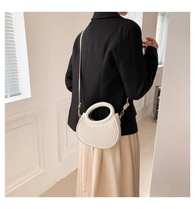 Détail d'un sac demi-lune plissé blanc crème avec poignée ronde et crochets dorés chic