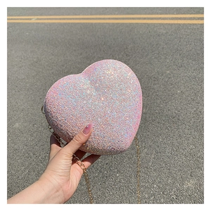 Close-up of pink sequined heart-shaped clutch bag with golden chain strap detail