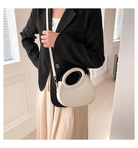 Détail du sac à main blanc semi-circulaire avec relief rayé et poignée ronde chic