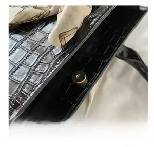 Detail view of black crocodile pattern faux leather handbag with golden magnetic buckle
