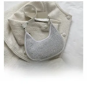 Detail view of a white crescent moon bag with silver rhinestones and leather strap