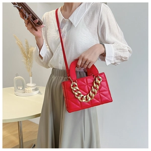Detail of red quilted shoulder bag featuring gold thick chain handle and leather strap