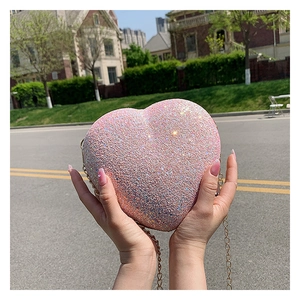Close-up of pink glitter heart-shaped bag with gold metal chain and shimmering texture