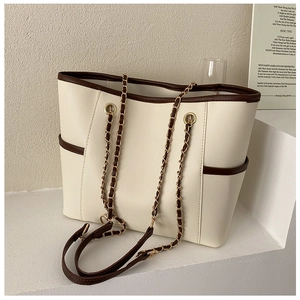 Detail view of cream white tote bag featuring gold chain straps and brown contrast piping