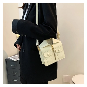 Close-up of cream white jacket-shaped shoulder bag with gold zippers and collar detail