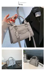 Detail view of grey faux leather handbag with zip pocket, fringe accents and long strap