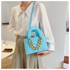 Close-up of light blue quilted leather bag with chunky gold chain and stitching detail