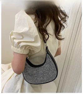 Close-up of a black crescent underarm bag with silver rhinestones on a model's shoulder