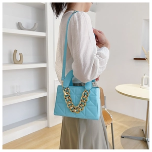 Detail of light blue quilted leather handbag with chunky gold chain handle and strap