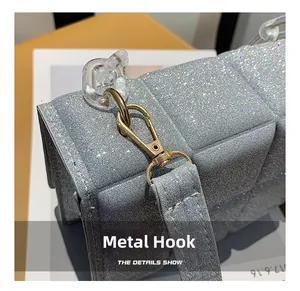 Close-up of golden metal hooks and acrylic chain on silver glitter shoulder bag