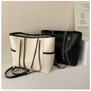 Detailed view of beige and black tote bags with chain straps on white steps decor