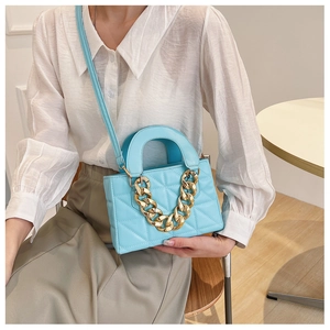 Close-up of light blue quilted handbag featuring a bold gold chain and elegant diamond pattern