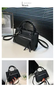 Detail of black faux leather handbag featuring fringe zipper and dual top handles